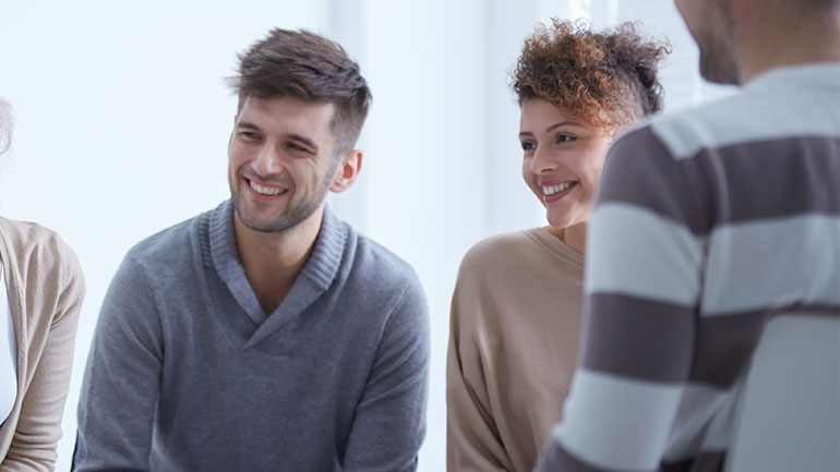 A group of people sitting in a support group smiling