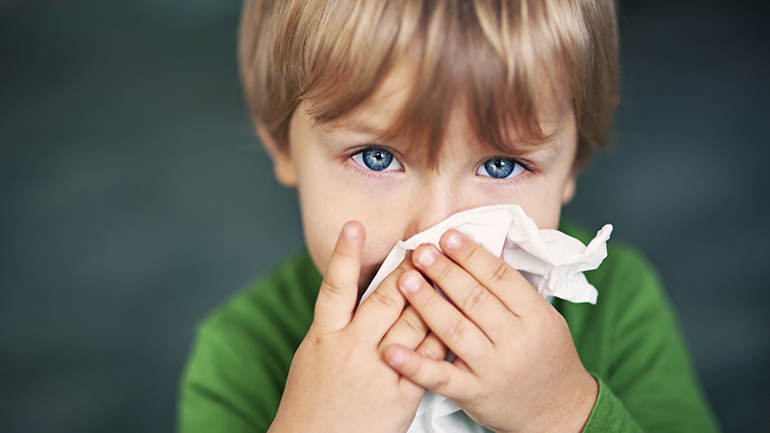 Portrait of a sick boy cleaning his nose