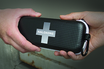 Two hands exchanging naloxone kit