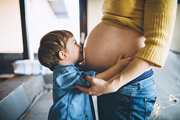 Little boy kissing mother's pregnant belly