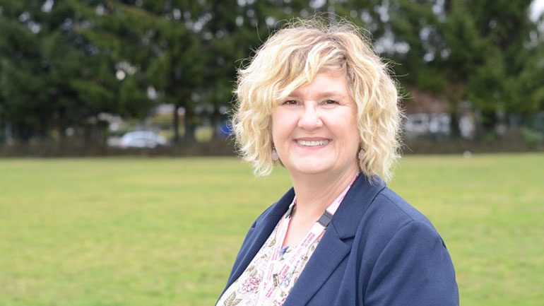 Photo of Wendy Clark standing in from of an open field.