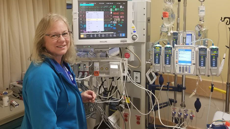 Dawn smiling at the camera with medical equipment behind her