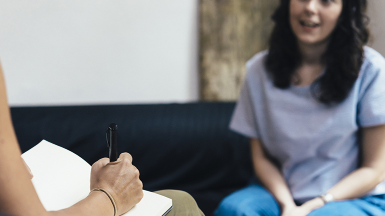 Health care provider taking notes while talking to a young girl