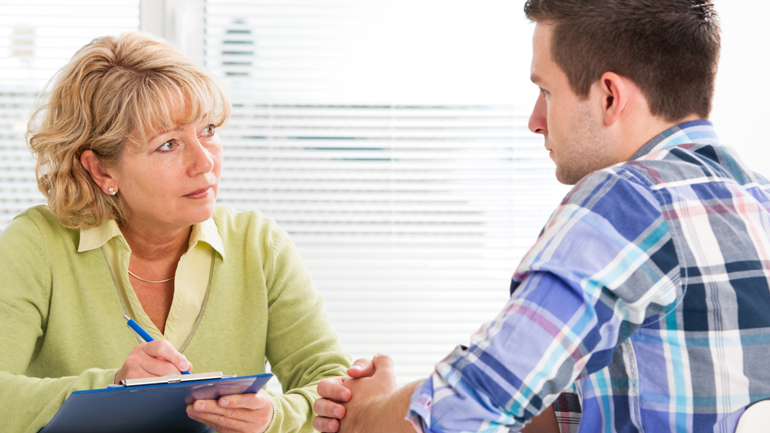 Woman writing down notes while consulting a young man