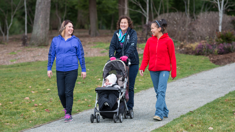 Moms walking their kids at a park.
