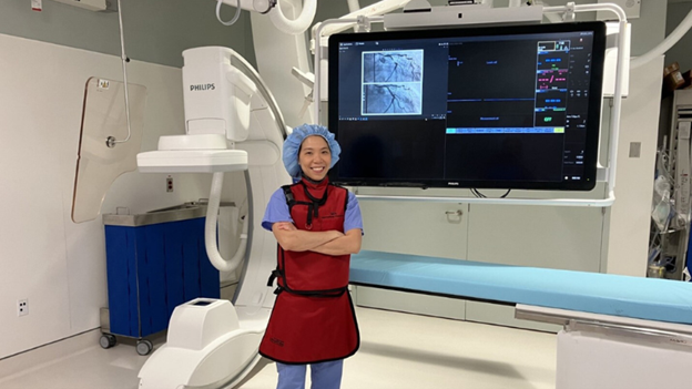 Nurse wearing protective gear standing in front of medical equipment.