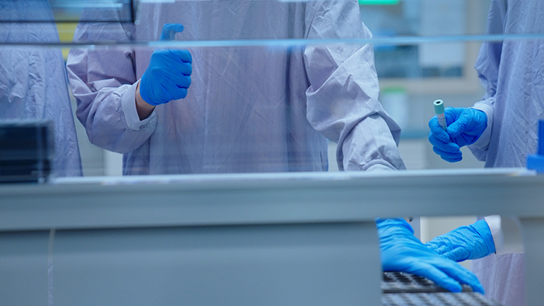 Laboratory workers wearing personal protective equipment handling test tubes