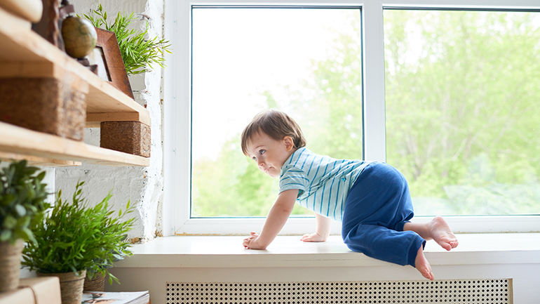 Young toddler climbing near window