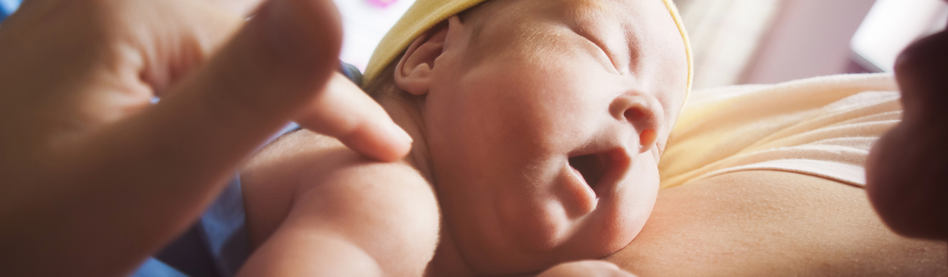 Premature baby sleeping on mother's breasts closeup