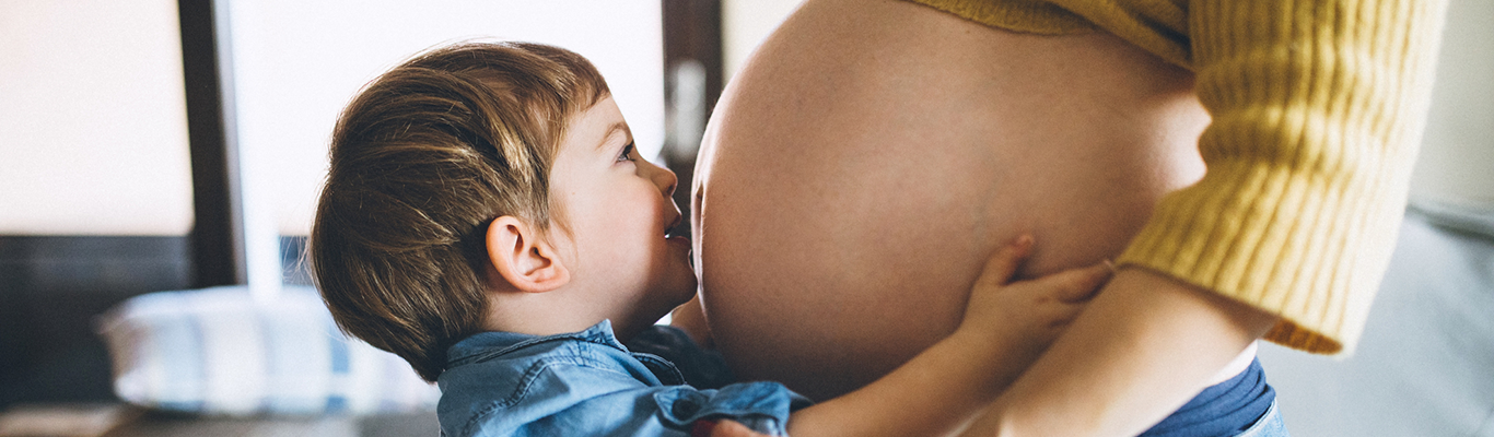 Little boy kissing mother's pregnant belly