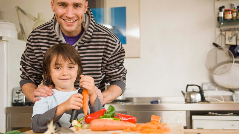 Father and son cooking peeling carrot