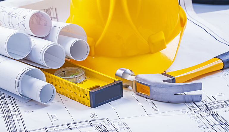 Various construction related objects including a hard hat, blueprints and a hammer.