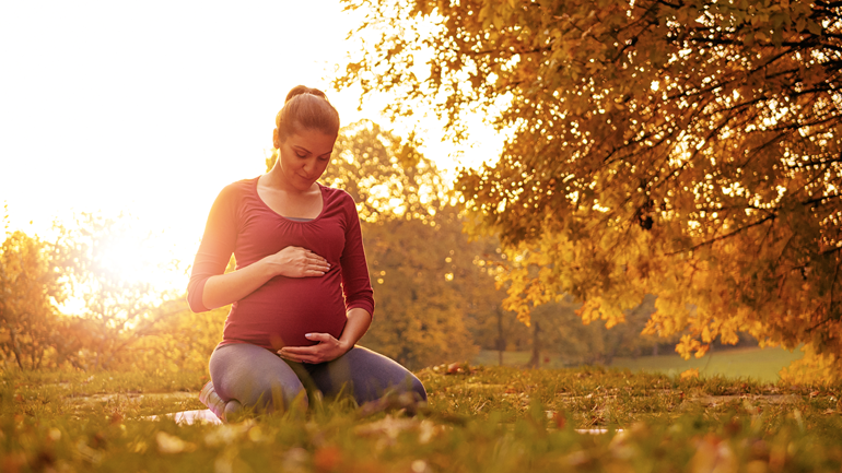 Pregnant woman practising yoga outdoors in the Fall