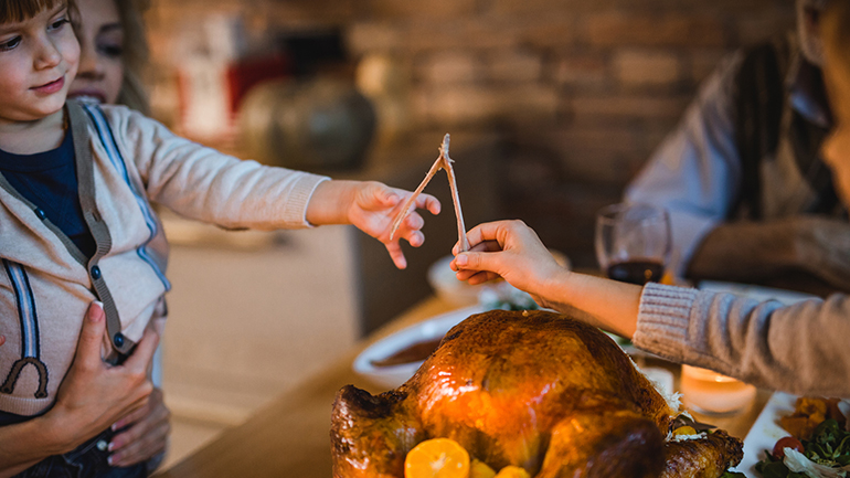 Two children passing a utensil over a thanksgiving turkey