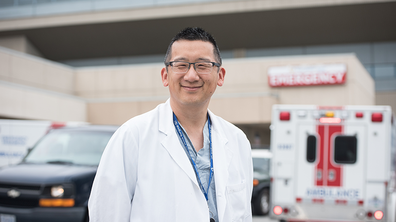 Dr. John Hwang standing outside Royal Columbian Hospital in front of ambulance