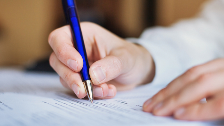 Close up of a hand filling out an application
