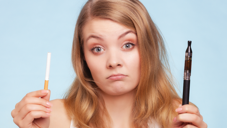 Woman holding a cigarette and an e-cigarette