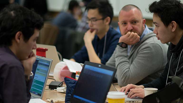 People discussing and looking at their computer during a hackathon