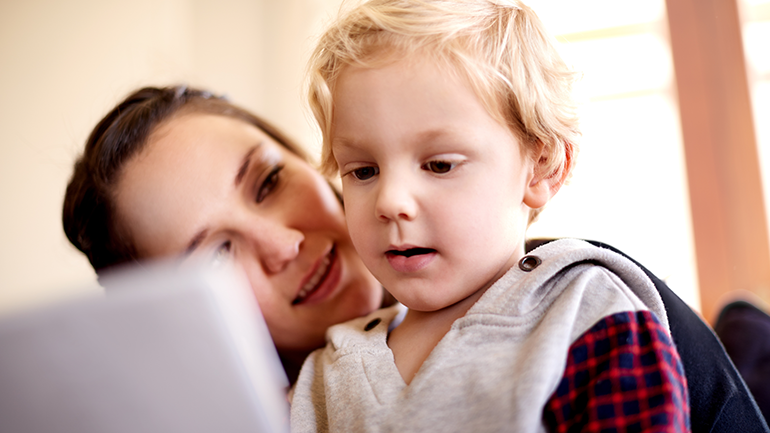Mother looking at the kid as he watches something on an iPad