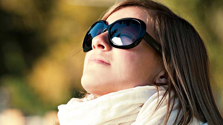 Woman wearing sunglasses looking up 