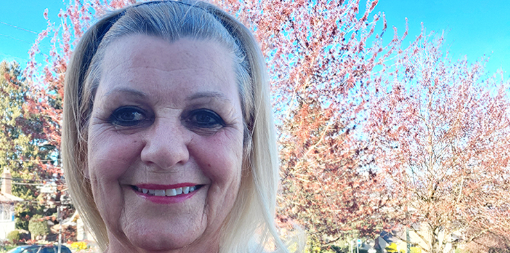 Darlene Gnam smiling and standing outside infront of trees