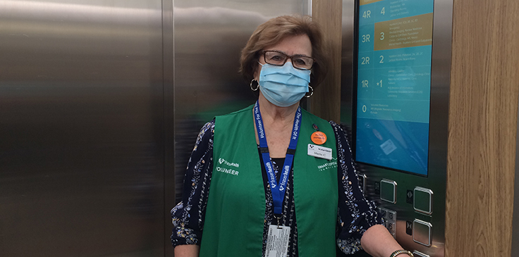 Maria Carinha standing in an elevator wearing a mask