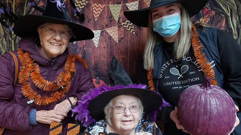 Three people dressed up in witches hats with Halloween decor.