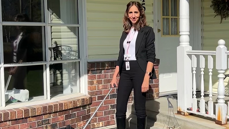 Dental Hygienist Nishi Lal-Birdi standing in front of a house with a luggage bag